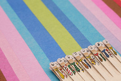 Matchsticks with faces painted on the heads on multicolored paper