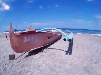 Boat moored on beach against sky