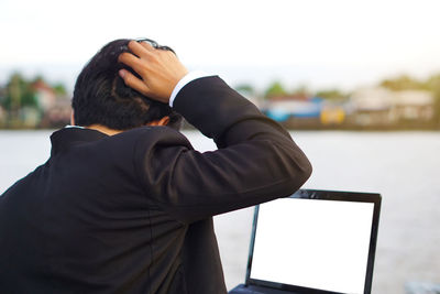 Rear view of man using mobile phone against sky