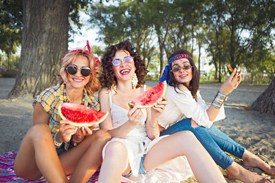 Cheerful friends eating watermelon at beach