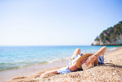 Man relaxing on beach against sky