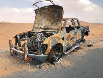 Old rusty wheel on field against sky