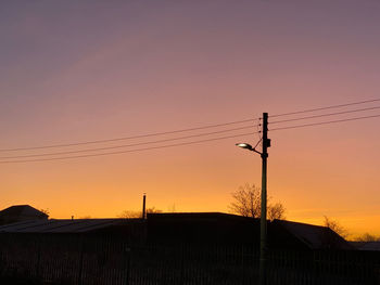 Silhouette electricity pylon against sky during sunset