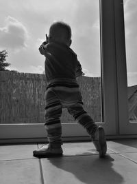 Rear view of baby girl standing by door at home