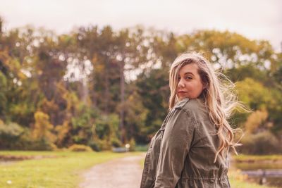 Portrait of young woman standing in park during autumn