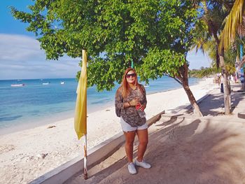 Full length portrait of smiling young woman on beach