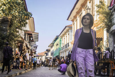 Young woman looking up while standing on street in city