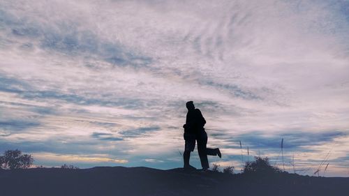 Rear view of silhouette man standing on land against sky