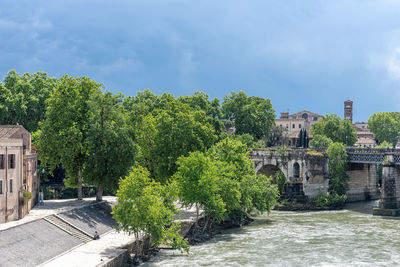 Arch bridge over river amidst buildings against sky