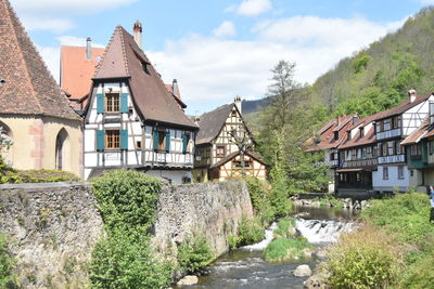 Houses by river in town against sky