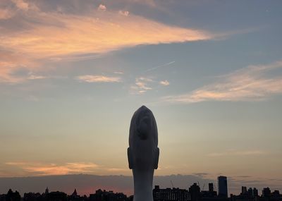 Statue in city against sky during sunset