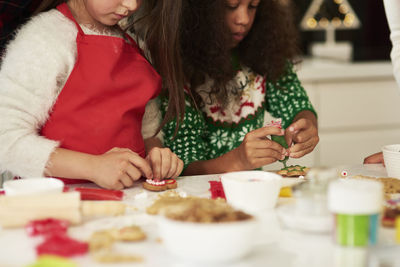 Midsection of siblings making cookies in kitchen