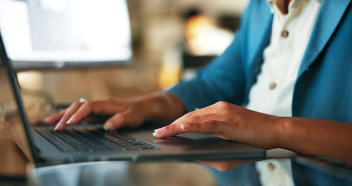 Midsection of woman using laptop on table