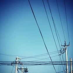 Low angle view of power lines against clear blue sky