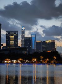 Illuminated buildings by river against sky at night