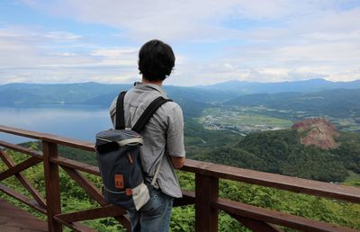 Rear view of man looking at mountains against sky