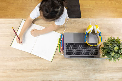 High angle view of girl using laptop on table