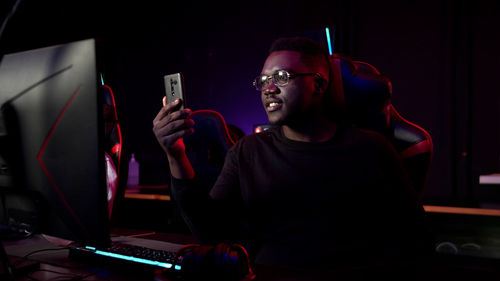 Man using mobile phone while sitting in darkroom