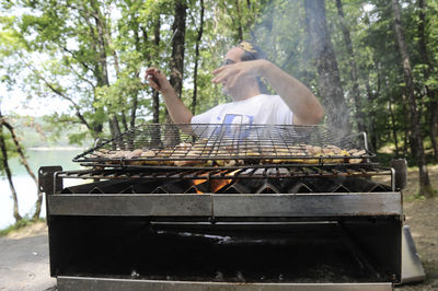Man preparing meat on barbecue grill in forest
