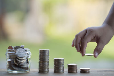 Cropped hand of child arranging coins on wooden table