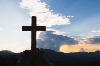 Silhouette cross against sky during sunset