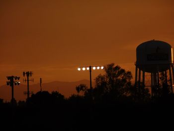 Silhouette trees against orange sky