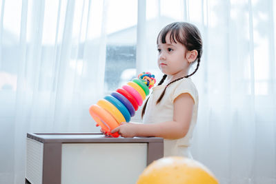 Girl playing with multi colored toys at home