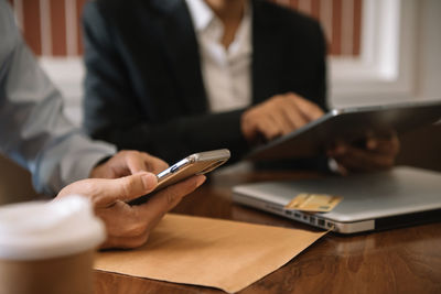 Midsection of man using mobile phone on table