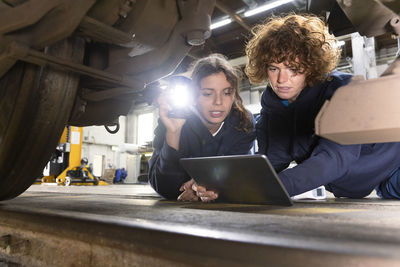 Engineer with trainee analyzing monorail wheel through tablet pc in factory