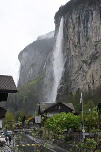 Scenic view of waterfall by buildings against sky