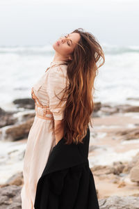 Woman with dress and harness at the beach on a windy day, portugal