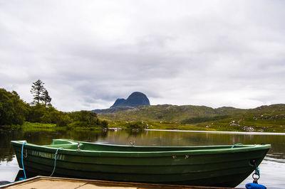 Boats moored by trees against sky