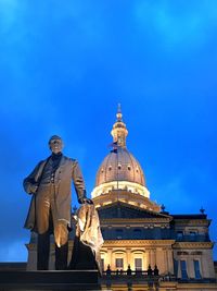 Low angle view of statue of building against blue sky