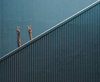 Cropped hands showing peace signs by wall