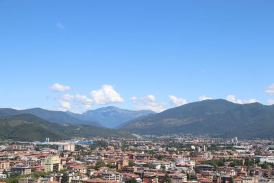 Townscape by mountains against blue sky