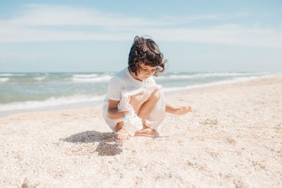 Rear view of boy on beach against sky