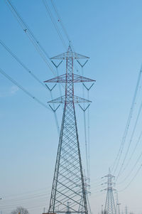 Low angle view of electricity pylon against clear blue sky