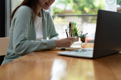 Midsection of woman using laptop on table