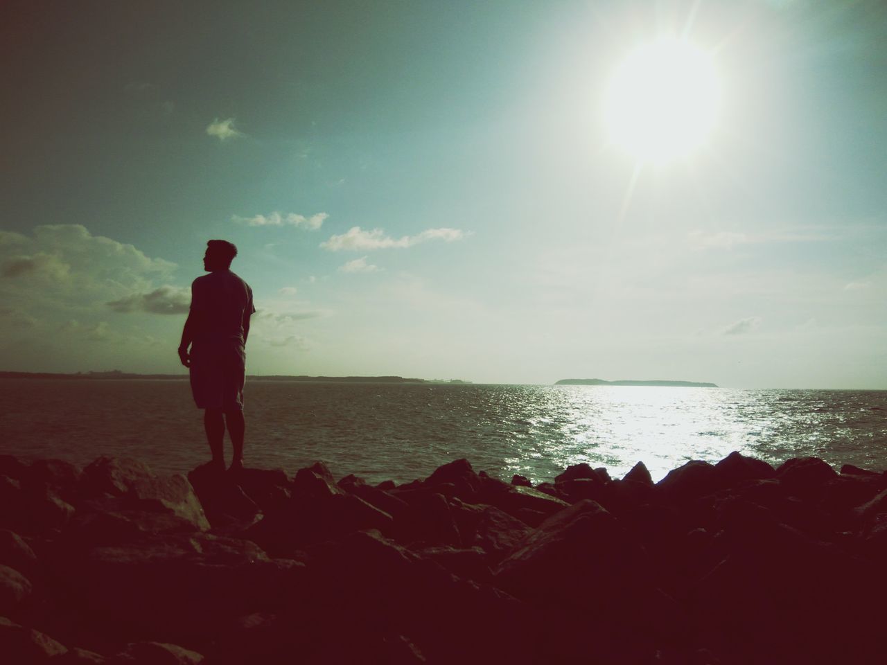 MAN STANDING ON SEA SHORE AGAINST SKY