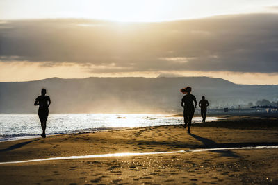 People on beach against sky during sunset