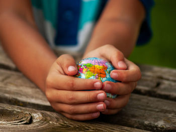 Midsection of boy holding globe on table