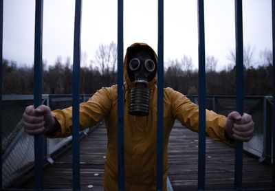 Man wearing gas mask while standing by metal against sky
