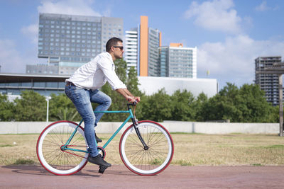 Side view of man riding bicycle on city