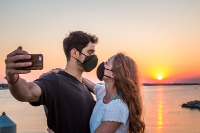 Portrait of friends photographing at sunset