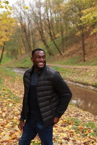 Portrait of smiling young man standing on land during autumn