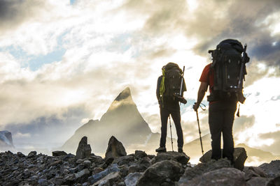 Rear view of backpackers approaching dramatic mountain summit, canada.