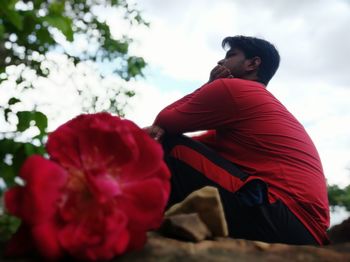 Side view of young man against red flowering plants