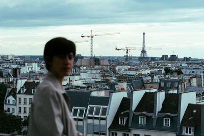 Man standing by buildings against sky in city