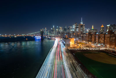 Illuminated bridge and buildings against sky at night