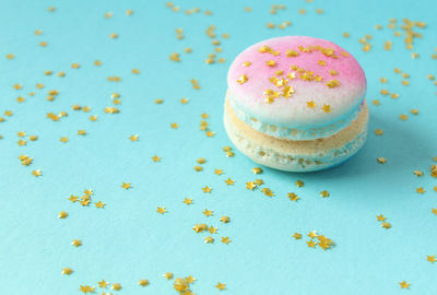 Close-up of macaroon and star shaped sequins on blue background